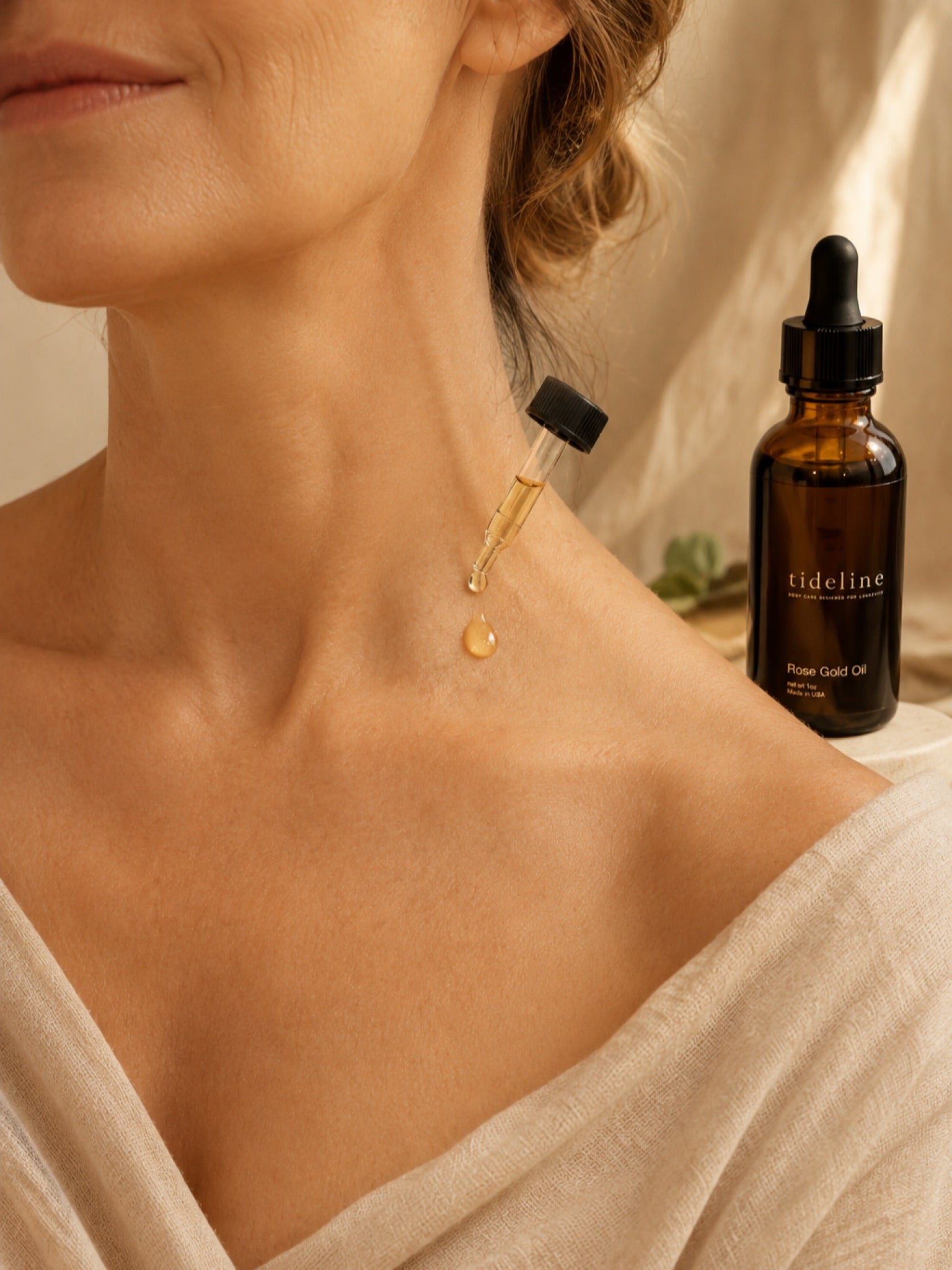Tideline Rose Gold Oil dispensed onto glowing skin in warm window light