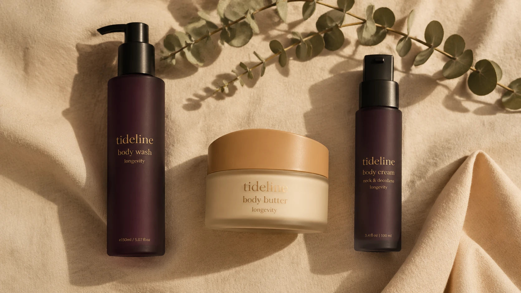 The three Tideline formulas arranged overhead on warm linen in soft light