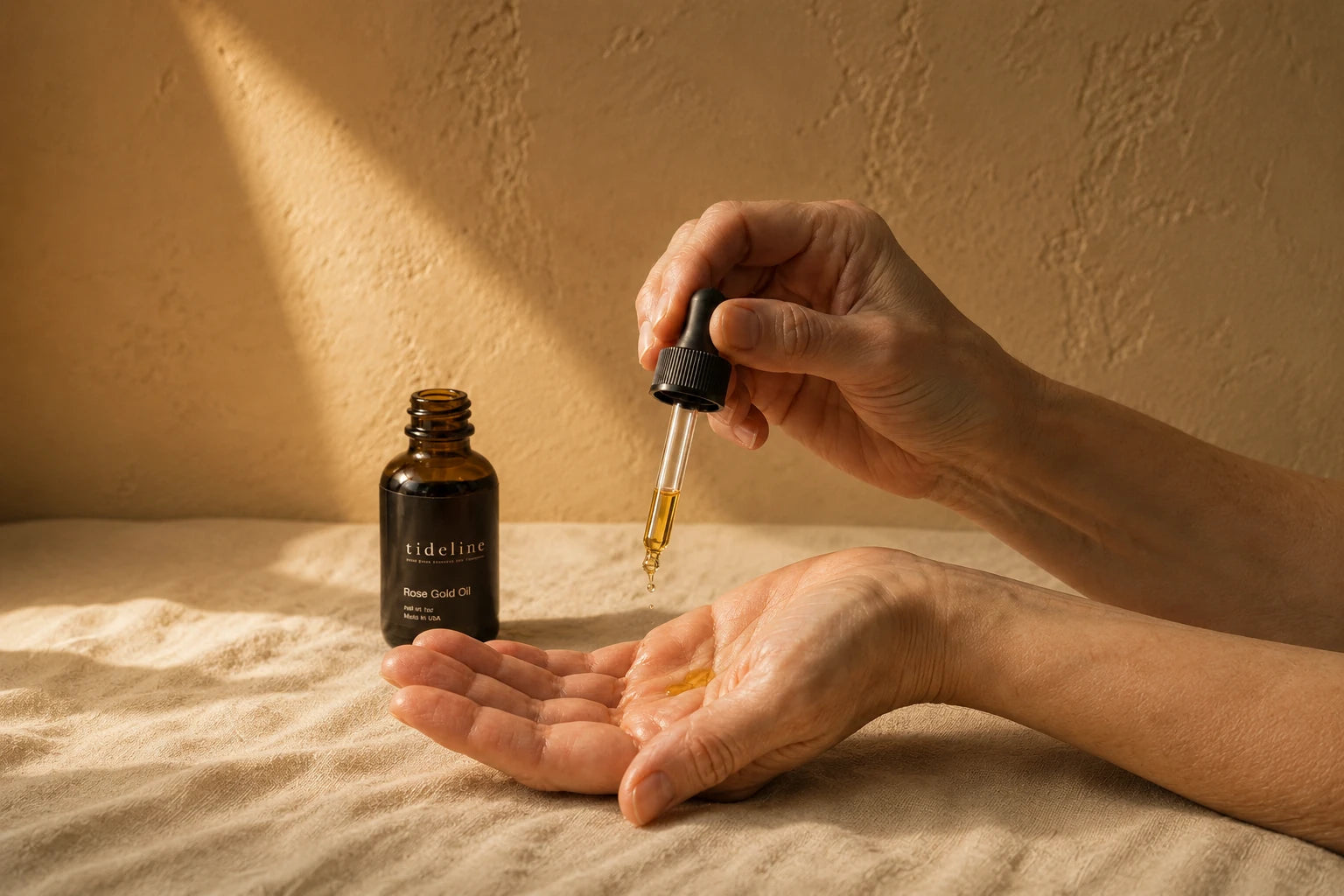 Rose Gold Oil dropped into an open palm, the bottle standing beside it