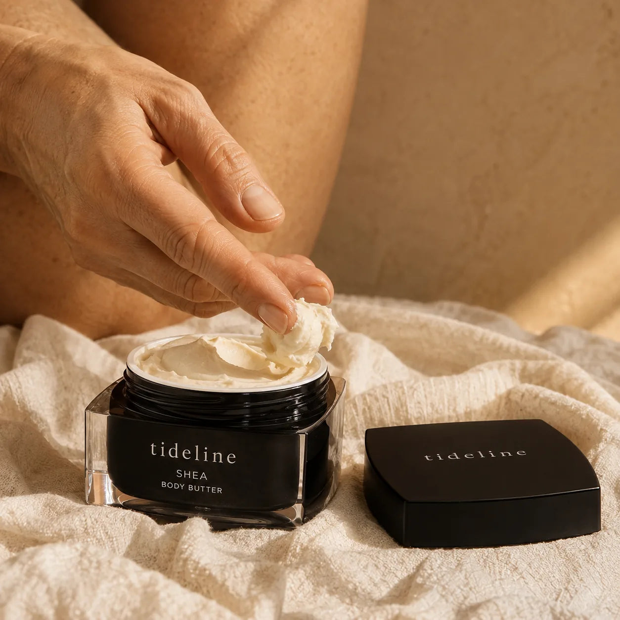 Fingers scooping Shea Body Butter from the open jar